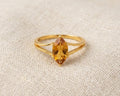18ct yellow gold ring featuring a marquise-cut honey citrine gemstone in a claw setting on a split-shank band, displayed on a light linen fabric background.