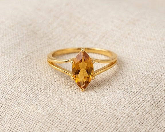 18ct yellow gold ring featuring a marquise-cut honey citrine gemstone in a claw setting on a split-shank band, displayed on a light linen fabric background.