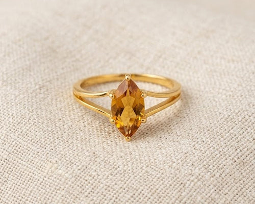 18ct yellow gold ring featuring a marquise-cut honey citrine gemstone in a claw setting on a split-shank band, displayed on a light linen fabric background.