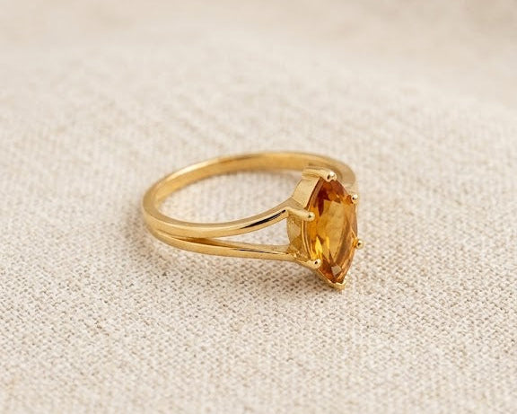 18ct yellow gold ring featuring a marquise-cut honey citrine gemstone in a claw setting on a split-shank band, displayed on a light linen fabric background.