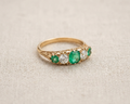 Emerald and diamond anniversary ring featuring an alternating row of three green emeralds and two old-cut diamonds in yellow gold, antique-inspired jewelry for women, green gemstone five-stone band.