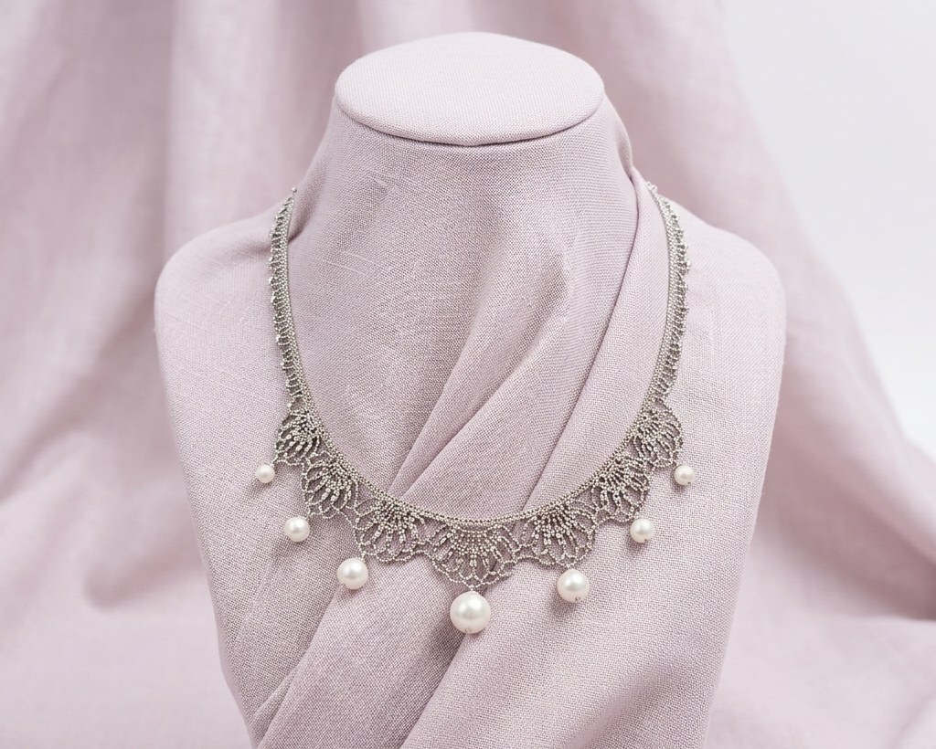 Vintage-inspired silver filigree lace collar necklace with seven graduating white pearls on a mauve linen bust display.