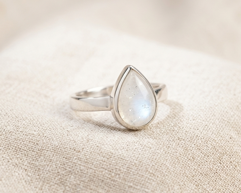 Side view of a teardrop-shaped natural moonstone ring in a polished sterling silver bezel setting