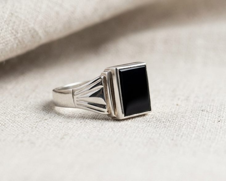 Side view of rectangular black onyx signet ring in sterling silver with geometric grooved detailing on the band.
