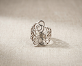 Handcrafted Sterling Silver Filigree Coil Ring with intricate abstract modern rose design and polished band, displayed on a textured light linen background.