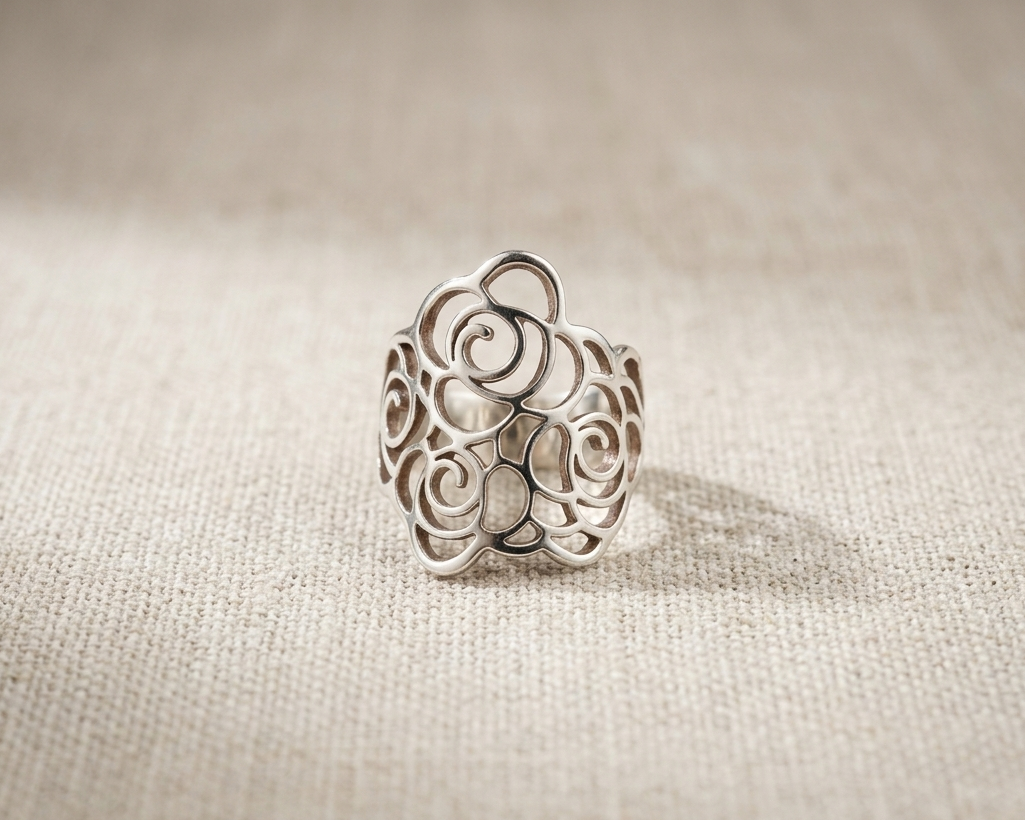 Handcrafted Sterling Silver Filigree Coil Ring with intricate abstract modern rose design and polished band, displayed on a textured light linen background.