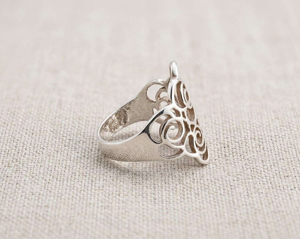 Handcrafted Sterling Silver Filigree Coil Ring with intricate abstract modern rose design and polished band, displayed on a textured light linen background. Side view.