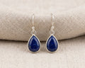A pair of elegant, deep cobalt blue teardrop-shaped Lapis Lazuli gemstones set in high-polish sterling silver bezels, with silver hooks.