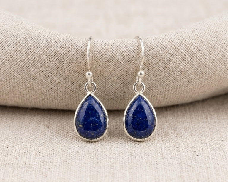 A pair of elegant, deep cobalt blue teardrop-shaped Lapis Lazuli gemstones set in high-polish sterling silver bezels, with silver hooks.