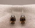 A pair of oval multifaceted smokey quartz earrings set in polished sterling silver prongs.