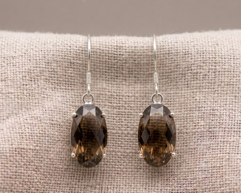 A pair of oval multifaceted smokey quartz earrings set in polished sterling silver prongs.