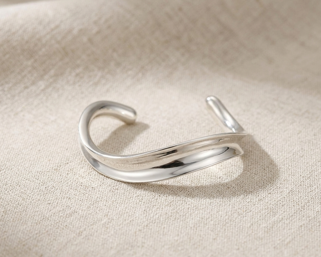 Sculptural sterling silver wide-wave bangle with a high-polished mirror finish.