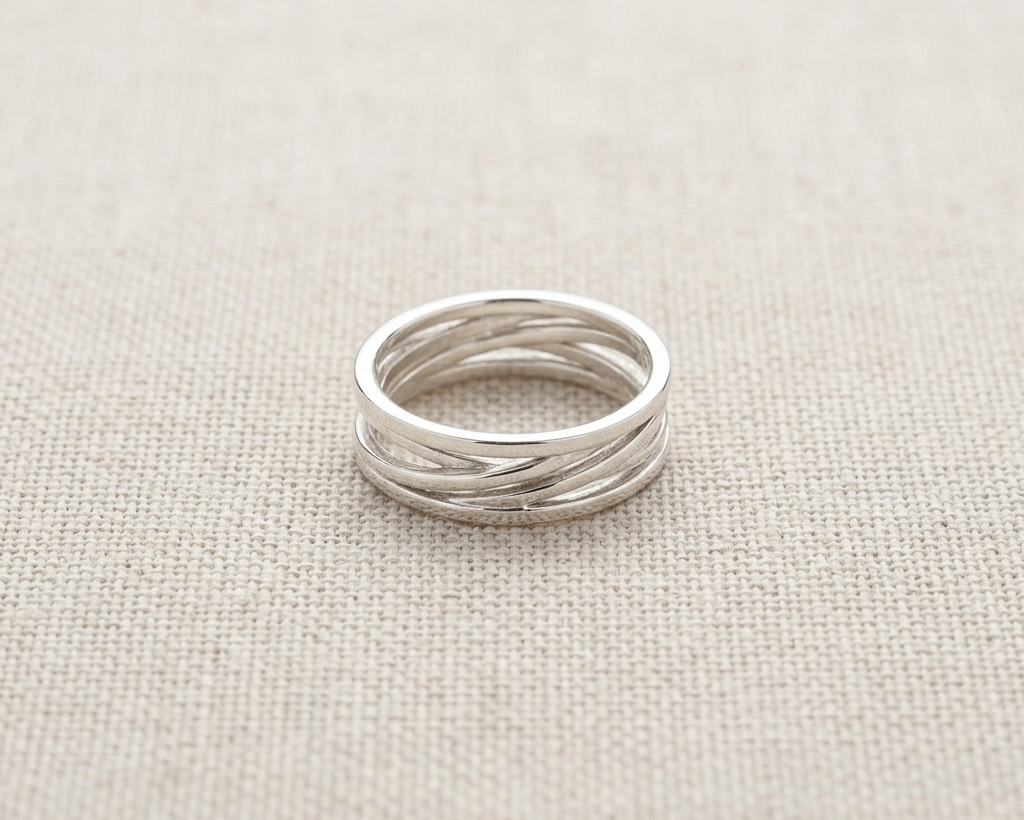 Alternate angle of the handcrafted high-polish .925 sterling silver multi-band 'interwoven' or 'twisted' design ring, set against a light, textured linen fabric background.